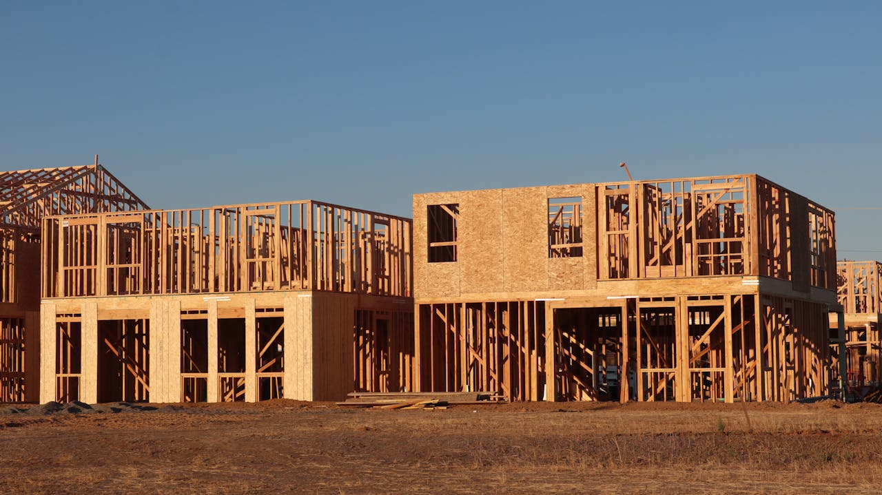 Wooden frames of new homes under construction in Elk Grove, California, during daylight.